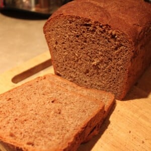 A loaf of chocolate bread with the end sliced off, on a wooden chopping board
