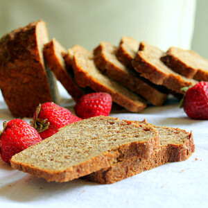 Slices of strawberry mango molasses loaf arranged with fresh strawberries