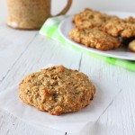 A quinoa raisin muffin cookie on a piece of parchment with a plate of cookies in the background