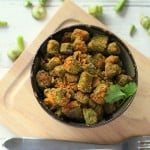 Bhindi Zunka in a dark bowl on a wooden chopping board