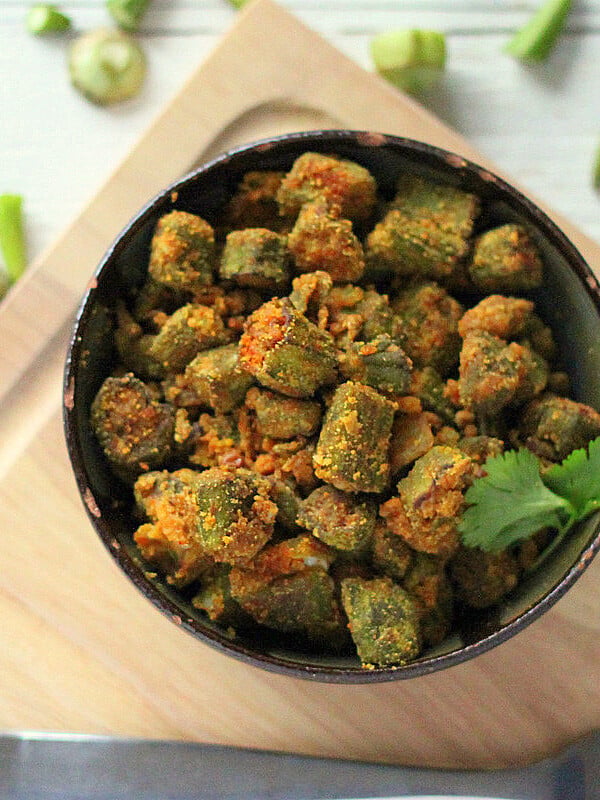 Bhindi Zunka in a dark bowl on a wooden chopping board