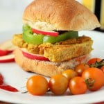 A tempeh frutter in a burger bun served with cherry tomatoes