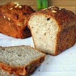 Two loaves of Sprouted Wheat Strawberry Bread cut in half on a work surface