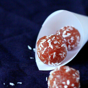 Pink coconut balls in a paper funnel on a dark background