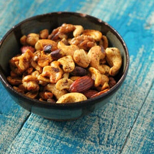 A bowl of spiced roasted nuts on a blue wood background