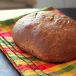 A loaf of faux sourdough bread on an orange and green gingham fabric