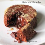 A molten lava cake on a white plate. A piece is broken away to show the melted chocolate centre