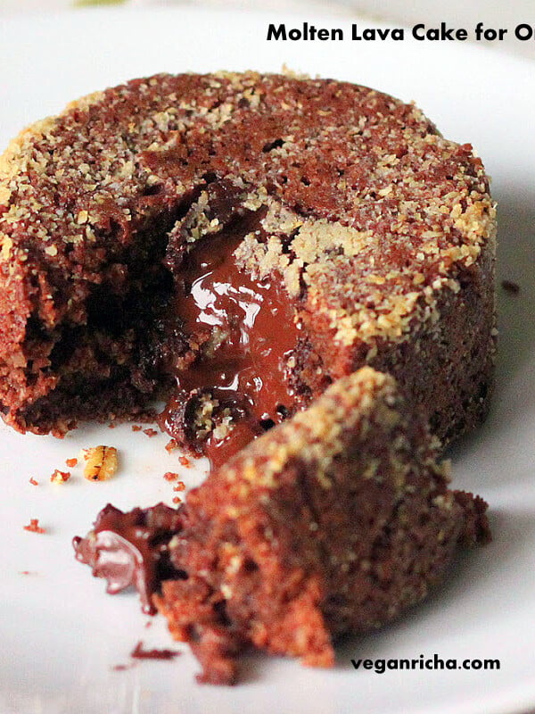 A molten lava cake on a white plate. A piece is broken away to show the melted chocolate centre