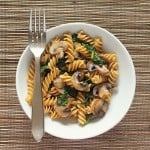 Mushroom fusilli in a white bowl with a fork. On a bamboo mat