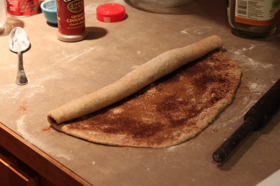 vegan cinnamon rolls cinnamon filled dough rectangle being rolled into a roll to make vegan cinnabons