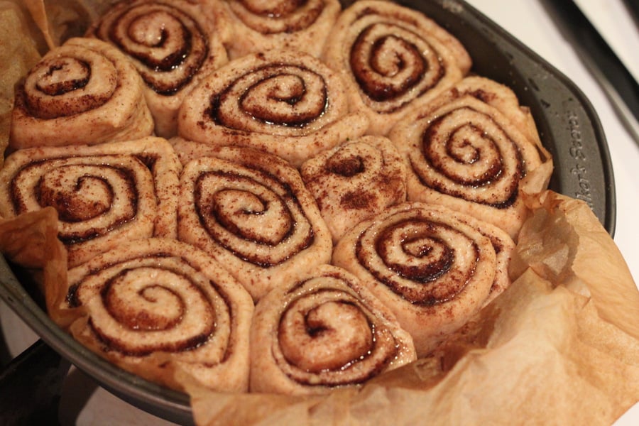 vegan cinnamon rolls risen vegan cinnamon buns in a round cake pan ready to be baked