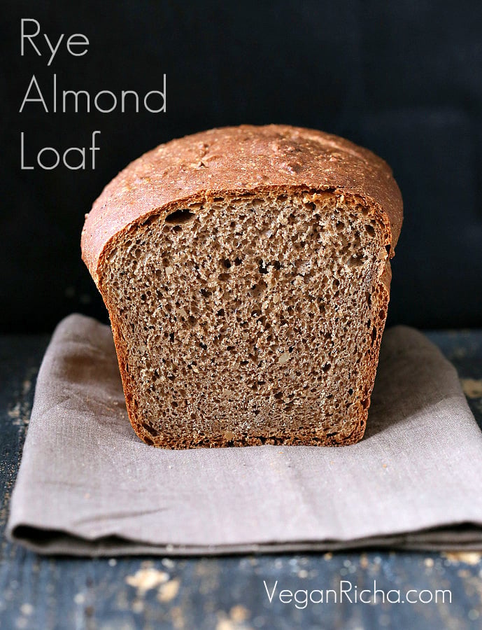 vegan burger buns a sliced-open loaf of whole wheat rye and almond flour sandwich bread on a light brown kitchen towel