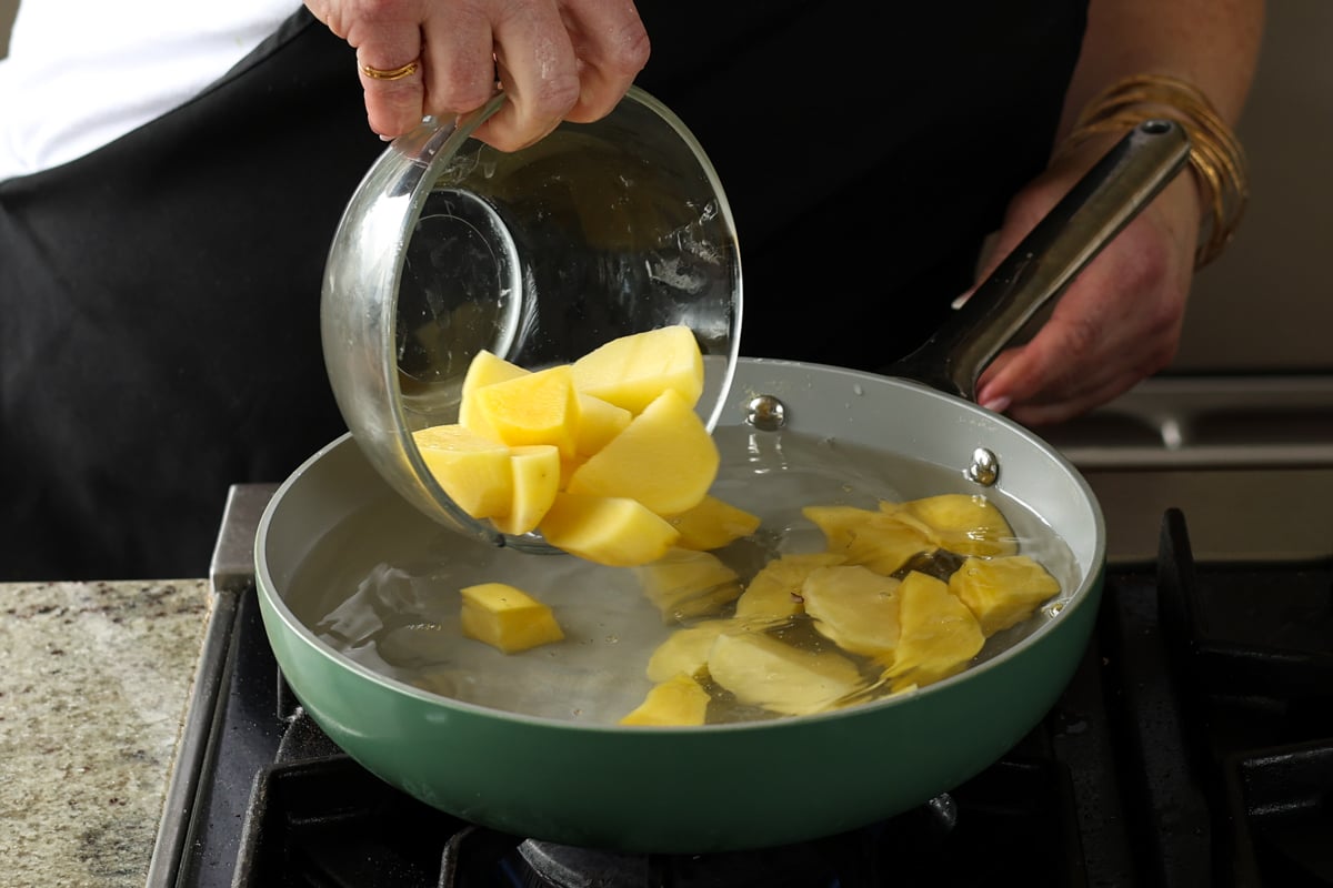 adding potatoes to the pan of water