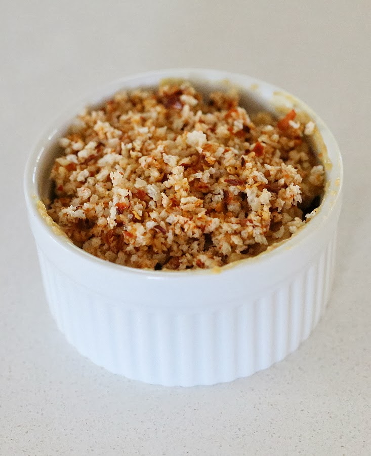 Cajun mac and cheese individual ramekins with dairy-free spicy mac and cheese being filled topped with vegan breadcrumbs