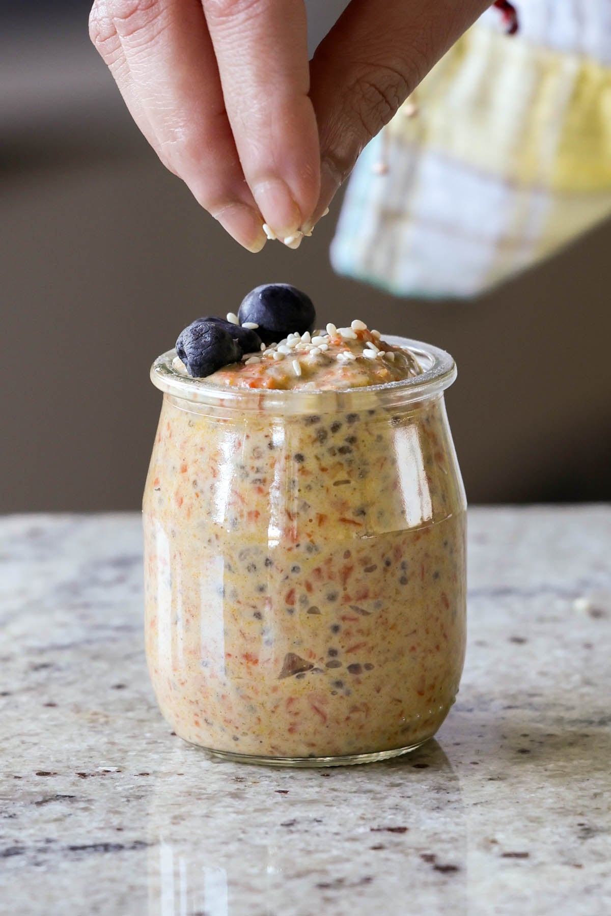 sprinkling pecans on top of carrot cake overnight oats