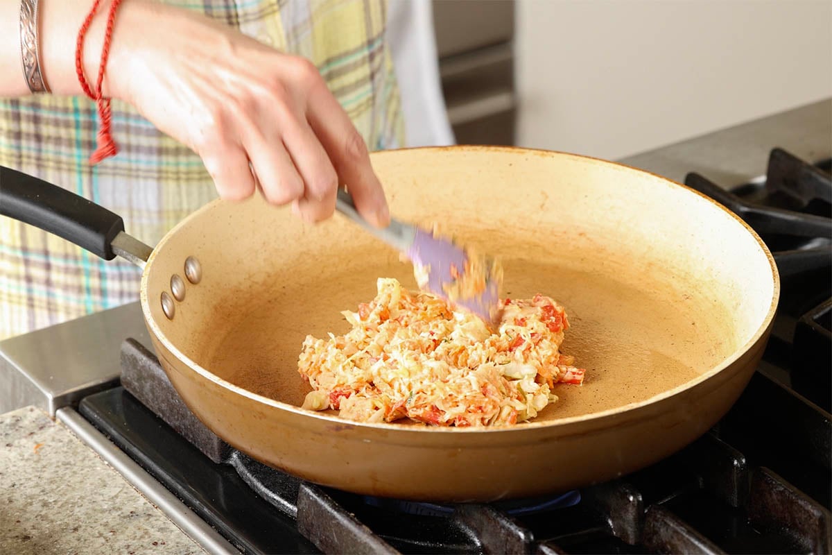 spreading out one of the okonomiyaki on the pan