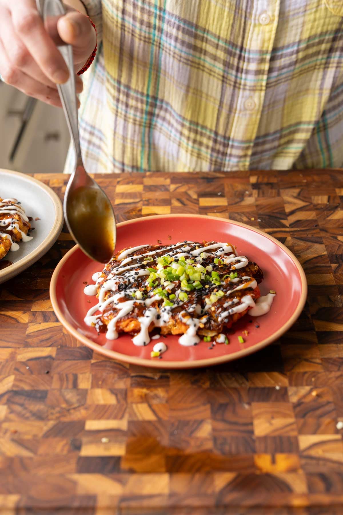 spooning the tonkatsu sauce onto the okonomiyaki
