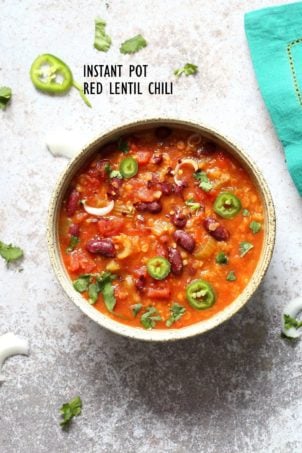 A bowl of instant pot red lentil chili on a white background with a turquoise napkin