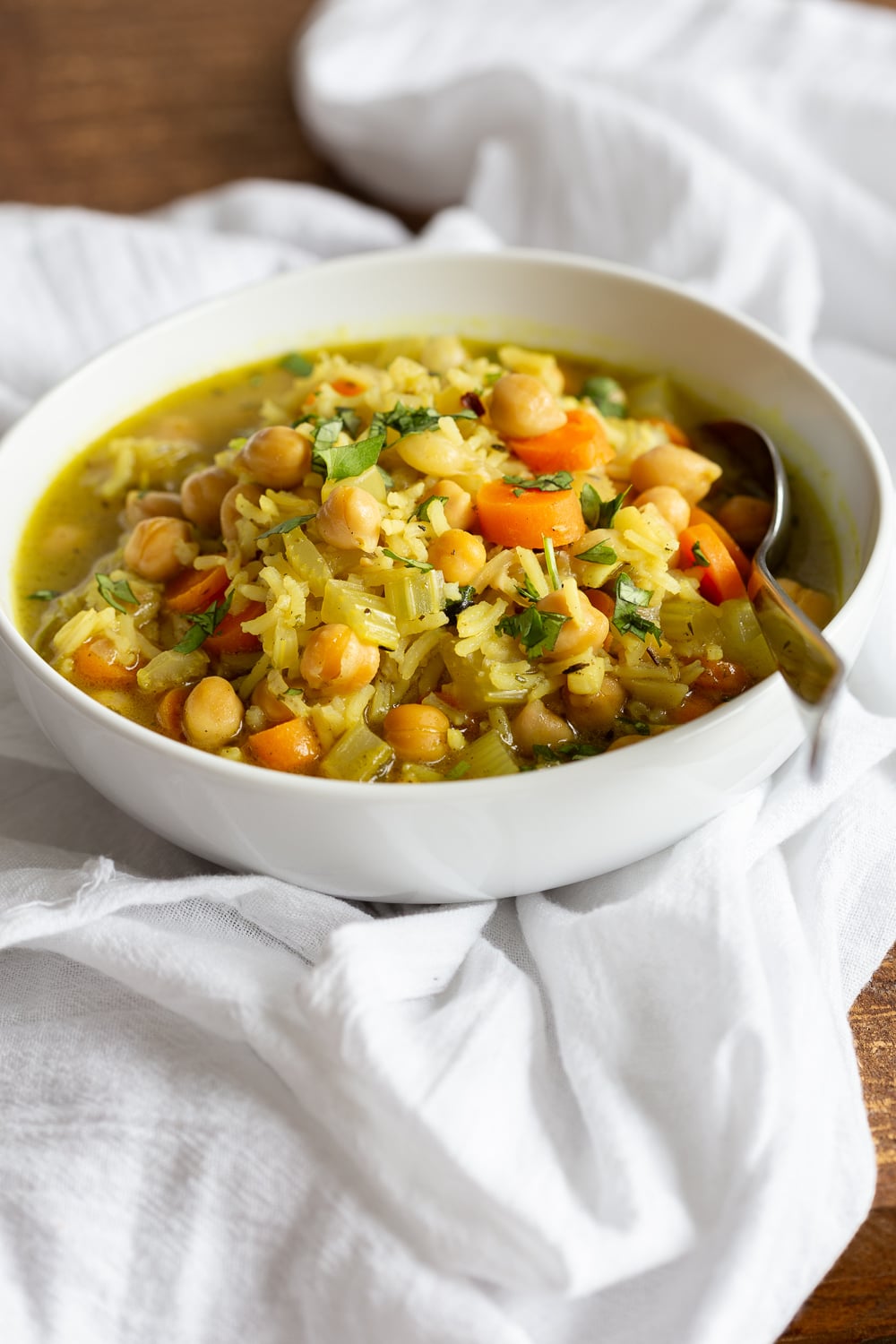 Vegan Chickpea Rice Soup in a white bowl over white cotton napkin