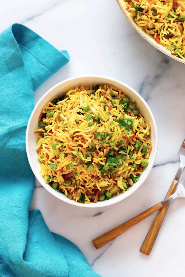 Top down shot of curry fried rice in a bowl with forks on a work surface