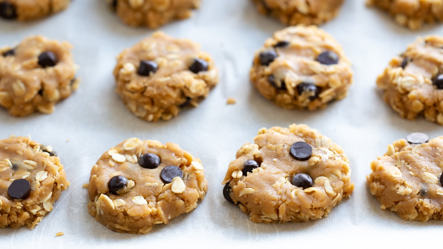 Vegan Peanut butter Oatmeal Chocolate chip Cookies on a parchment lined baking sheet
