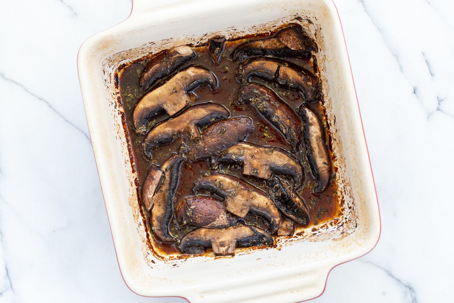 Marinated and baked portobello mushrooms in a stoneware baking dish for Our Creamy Vegan Mushroom Lasagna