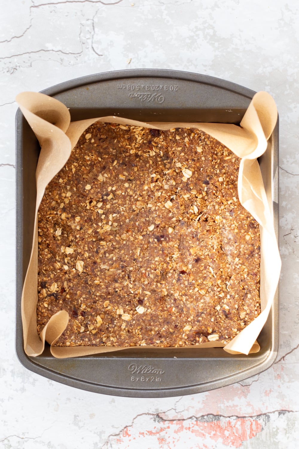vegan granola bars overhead shot of unbaked vegan banana granola bars in a metal baking pan