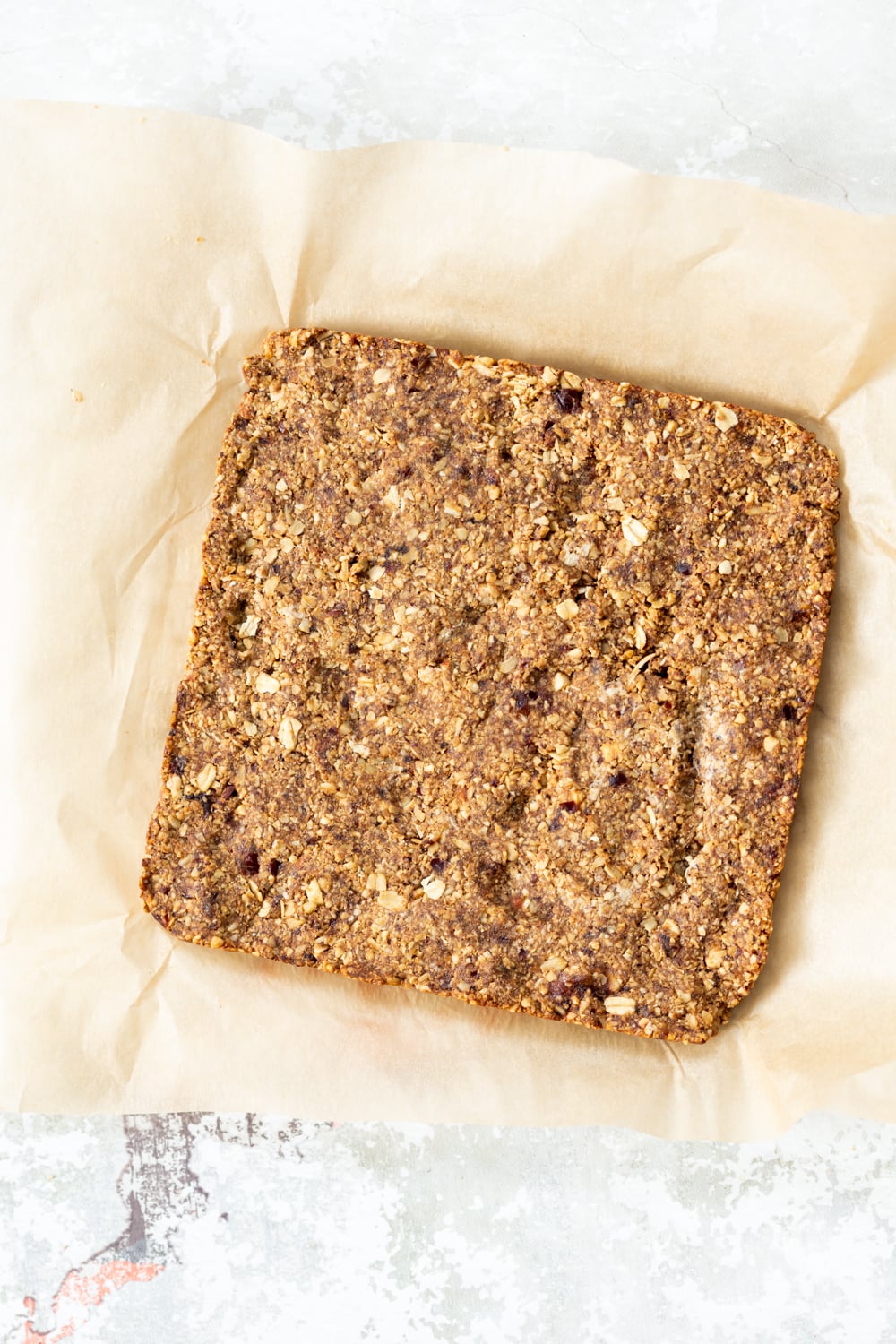 vegan granola bars overhead shot of vegan banana granola bars on a sheet of baking paper ready to be cut