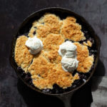 Our Vegan Blueberry Cobbler in a Cast Iron skillet over metal board