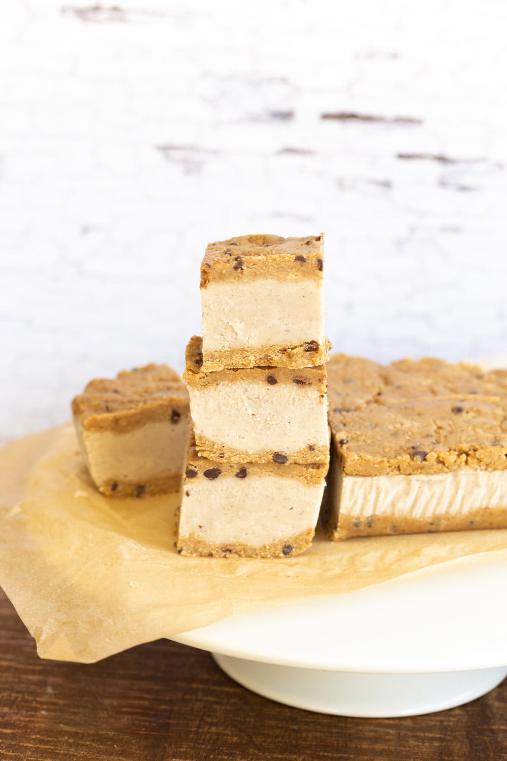 Vegan Cookie Dough Ice Cream Sandwiches stacked on a white cake stand