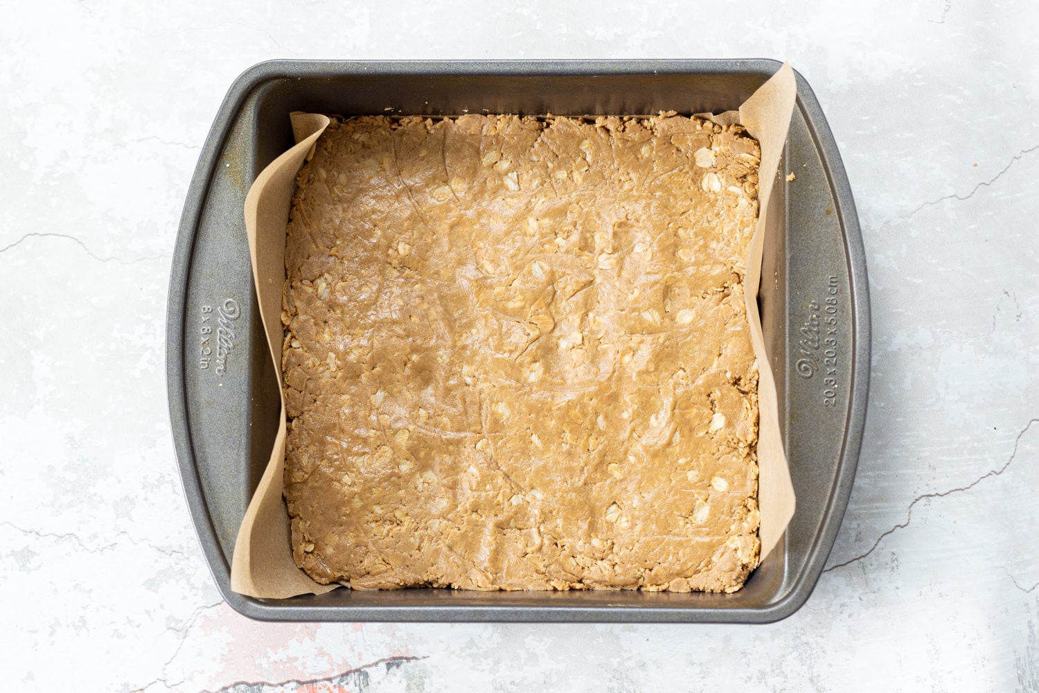 Oats and sunbutter mixture pressed into a parchment lined pan for our Sunbutter Granola bars