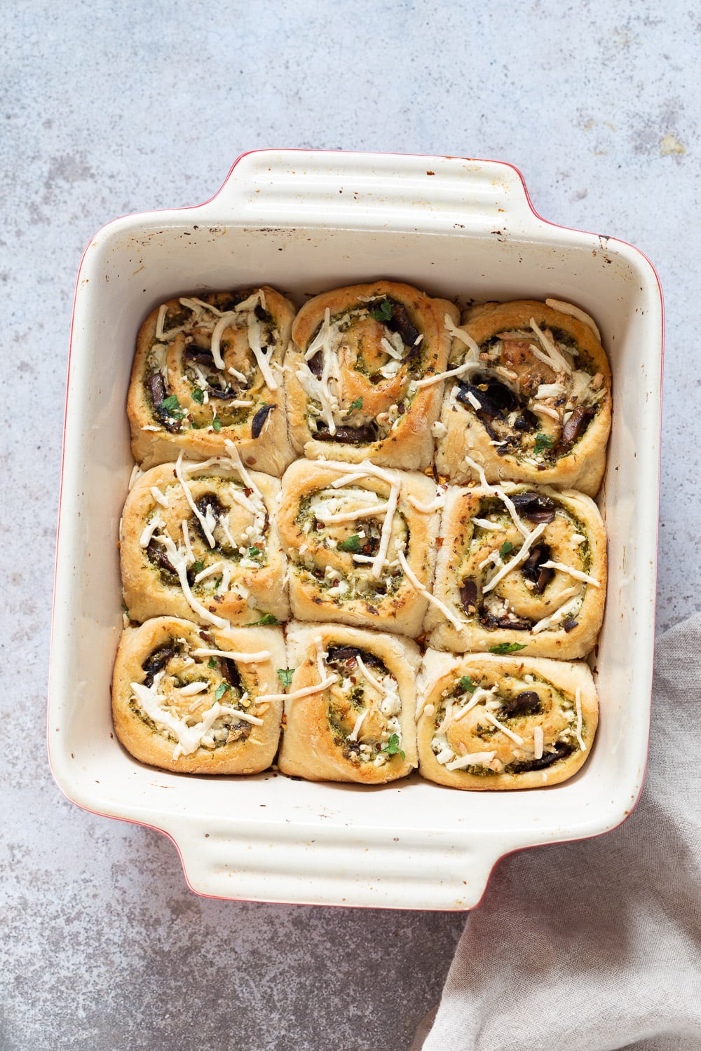 pizza rolls recipe overhead shot of vegan Pesto Pizza rolls in a ceramic baking dish