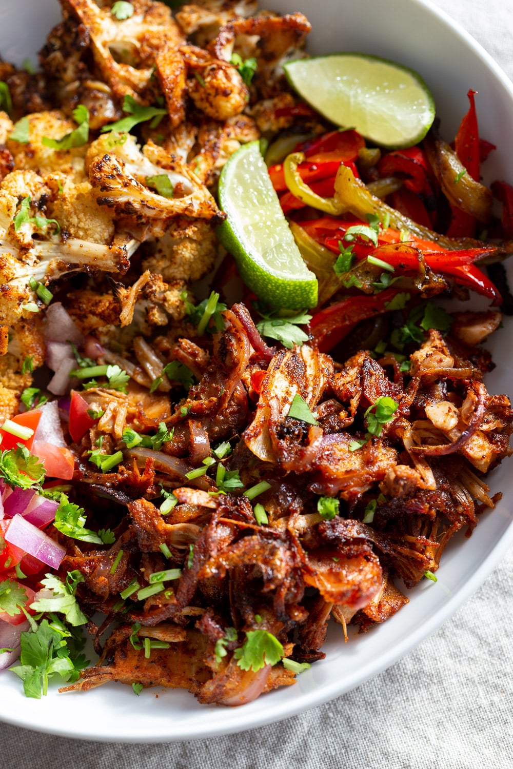Chili Lime Roasted Veggies & Jackfruit in a White Bowl to be drizzled with jalapeno cream sauce