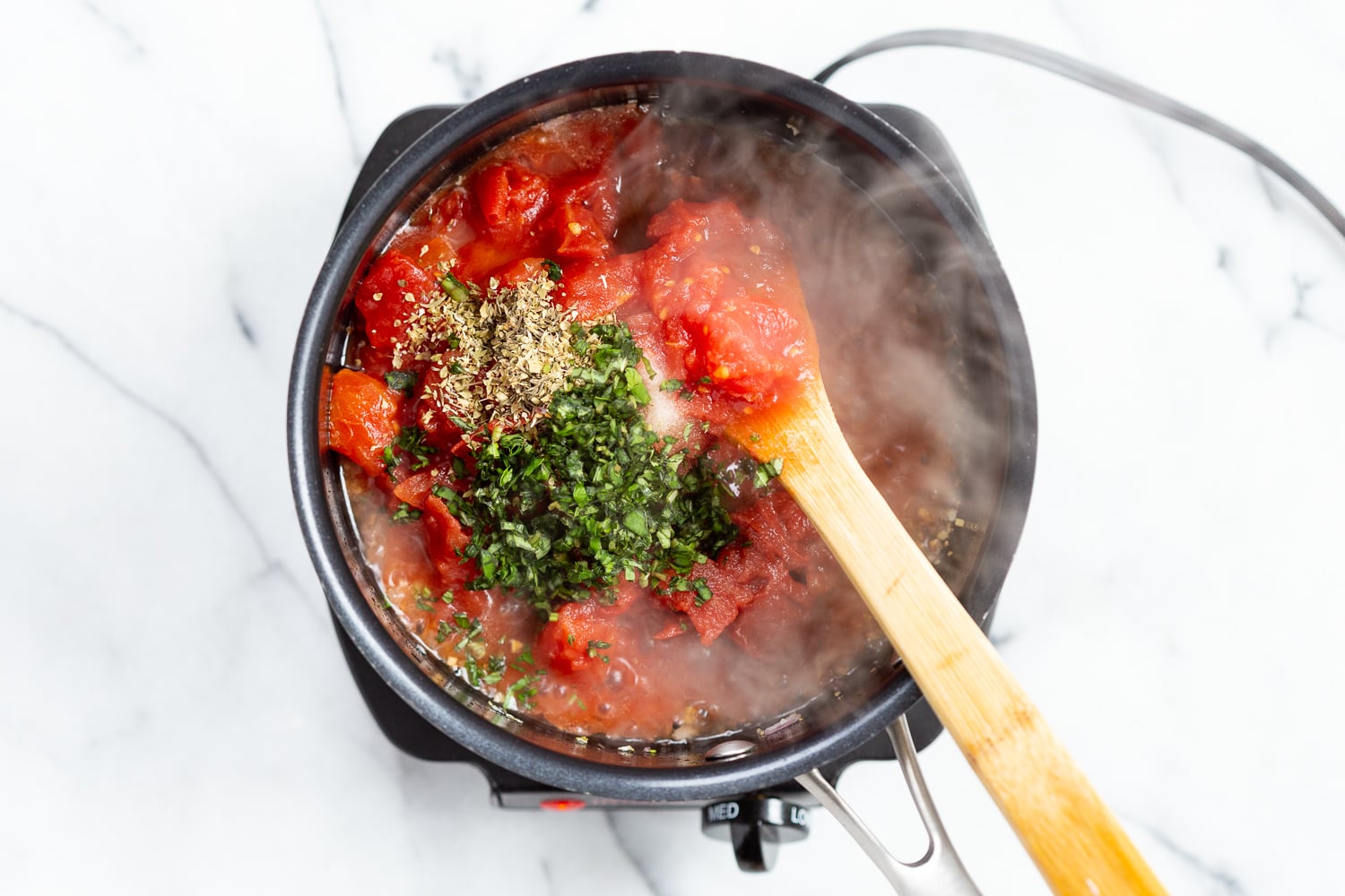 Ingredients for chunky marinara sauce in a black saucepan