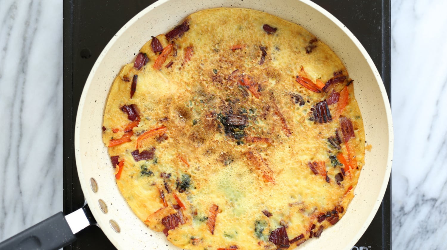 Veggie filled Vegan Omelet on a wite skillet