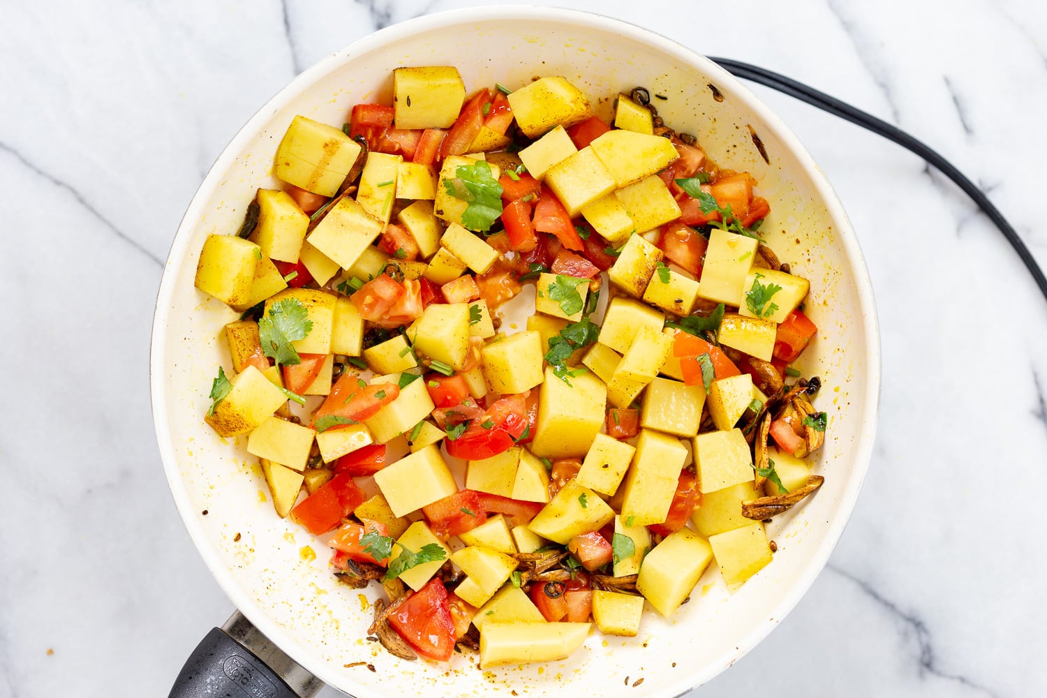 Potatoes and tomatoes in white skillet