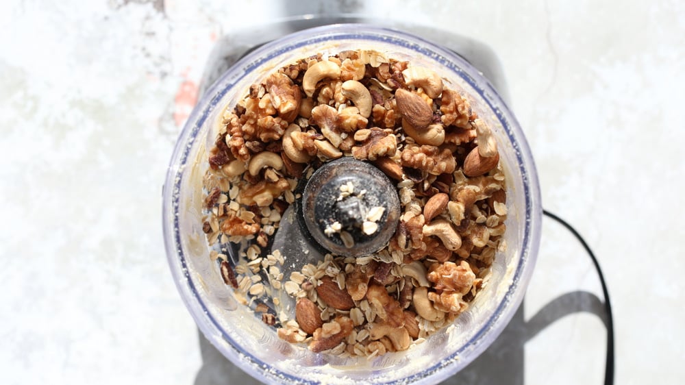 nuts and oats being added to a food processor