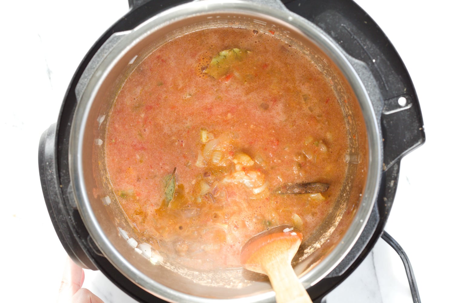 vegan curry recipe onions, garlic, tomato paste and spices being stirred in an Instant pot to make Vegan curry recipe