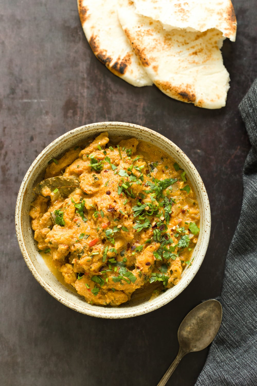 vegan curry recipe overhead shot of a bowl of vegan methi chicken with some naan bread on the side