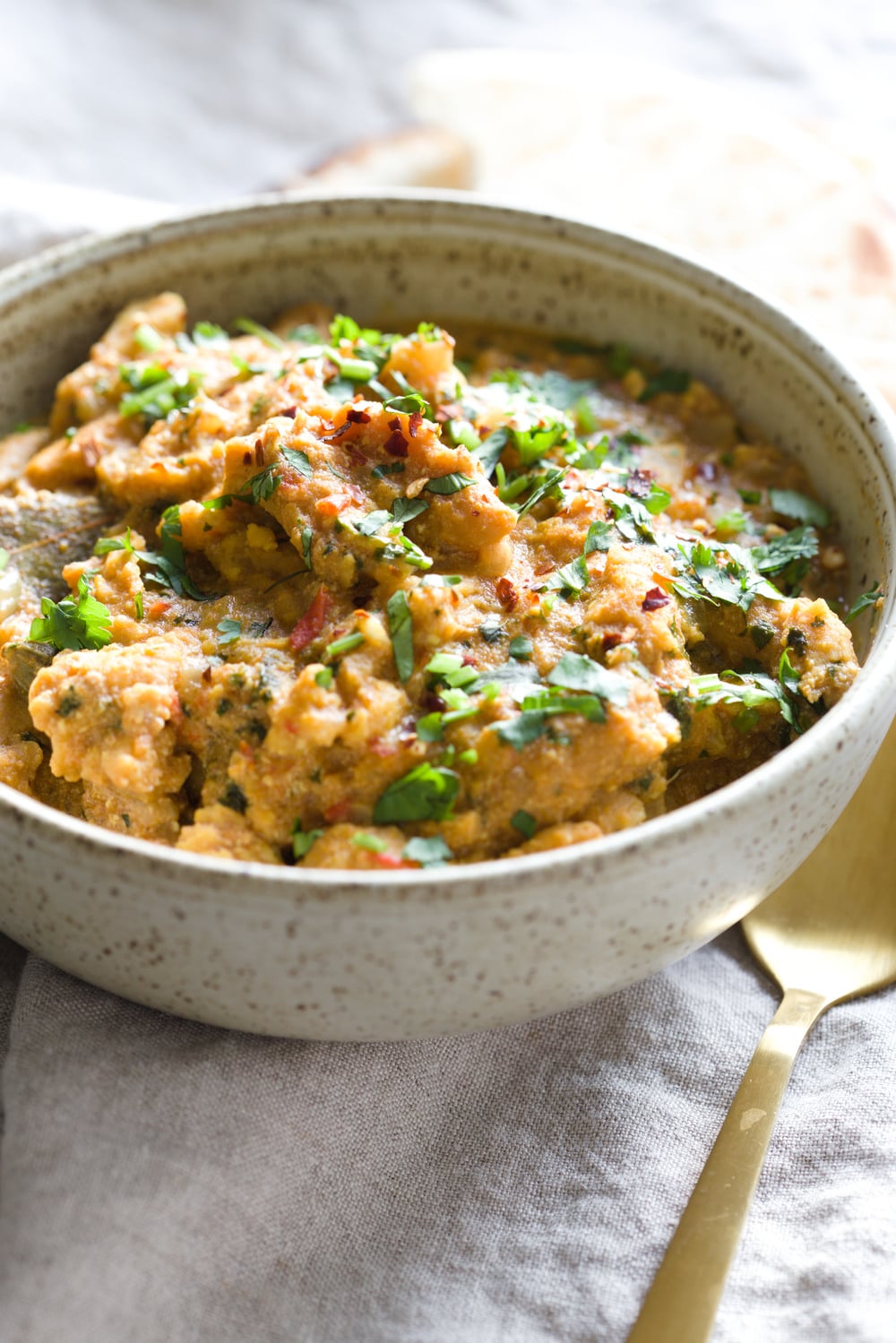 vegan curry recipe side view of a bowl of creamy vegan methi chicken curry topped with chopped cilantro