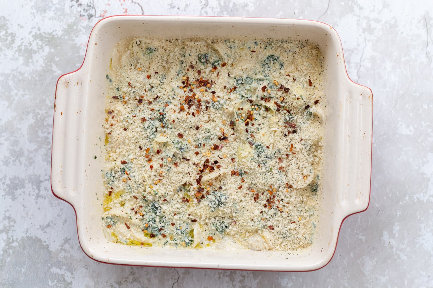 spinach artichoke pasta bake topped with breadcrumb topping ready to go in the oven