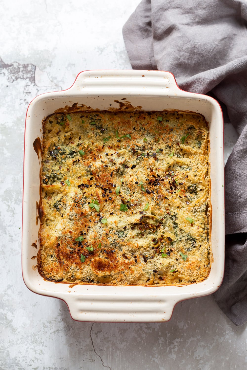 spinach pasta recipe overhead shot of a vegan spinach and artichoke pasta bake with breadcrumb topping