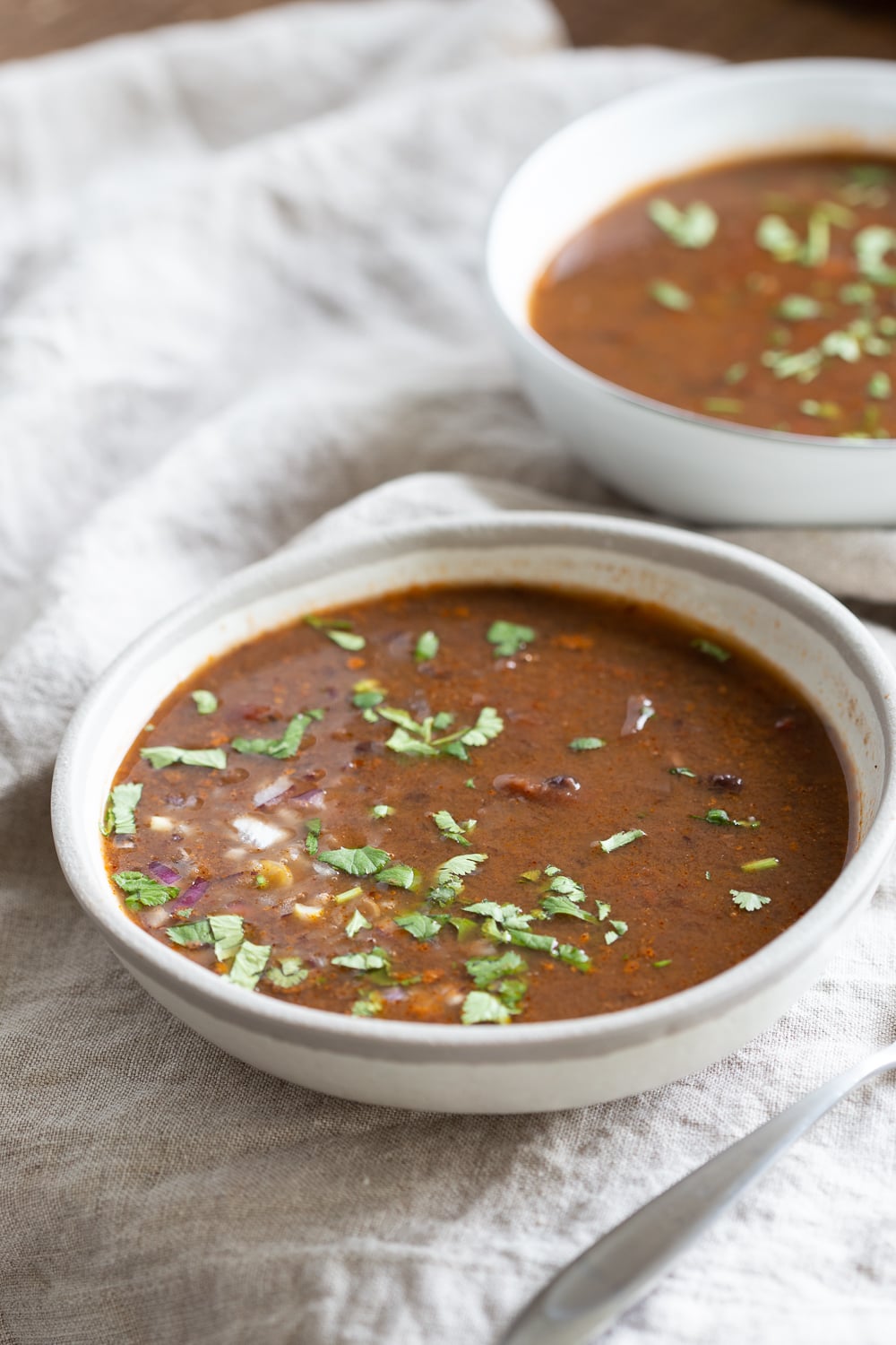 vegan black bean soup side view of a bowl of vegan Instant Pot black bean soup on a white cloth napkin