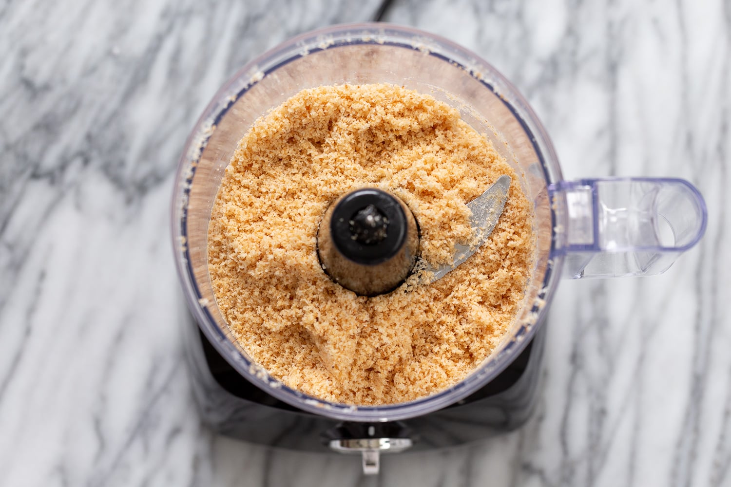 coconut balls overhead shot of a food processor filled with toasted coconut