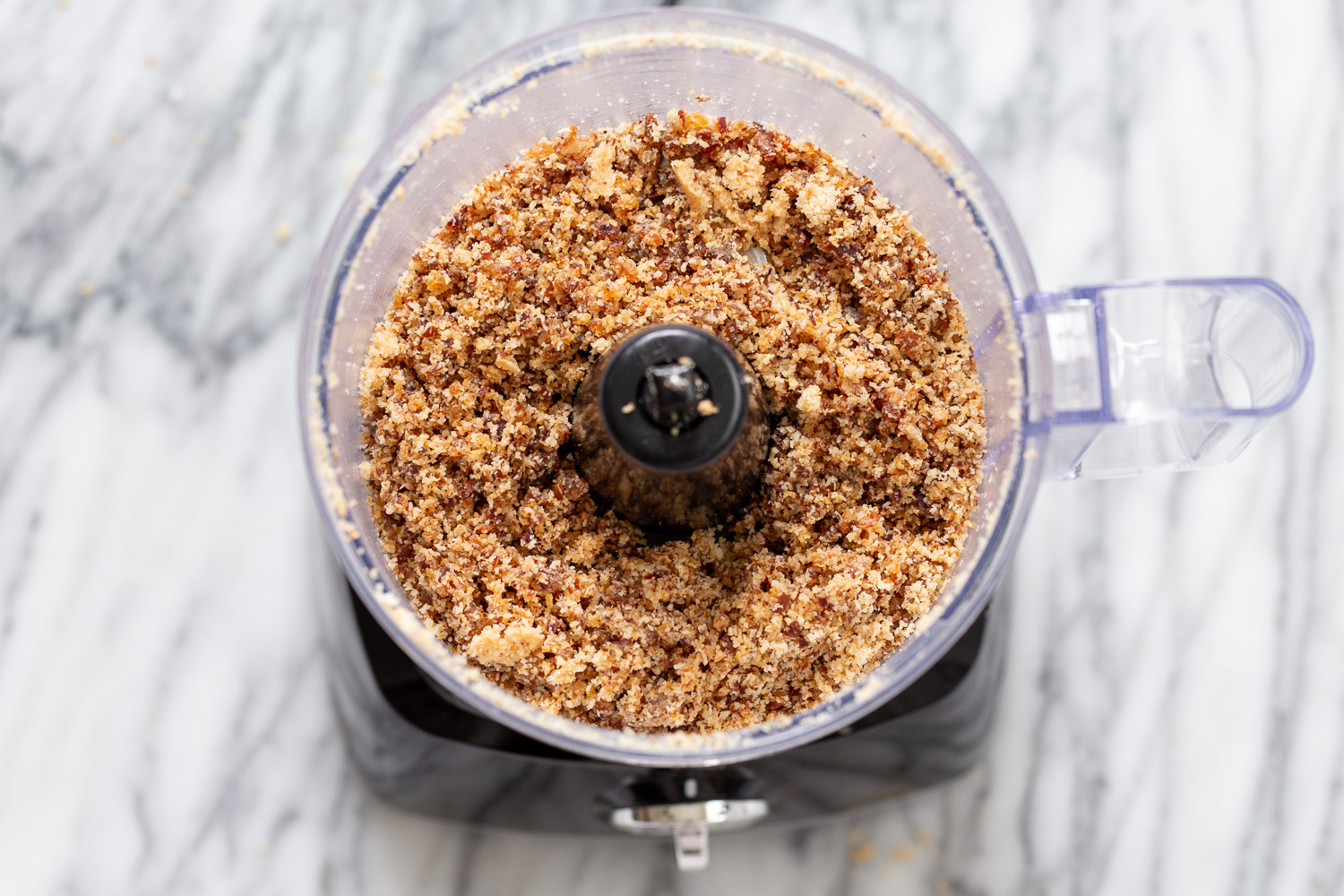 coconut balls shredded coconut and dates in the container of a food processor