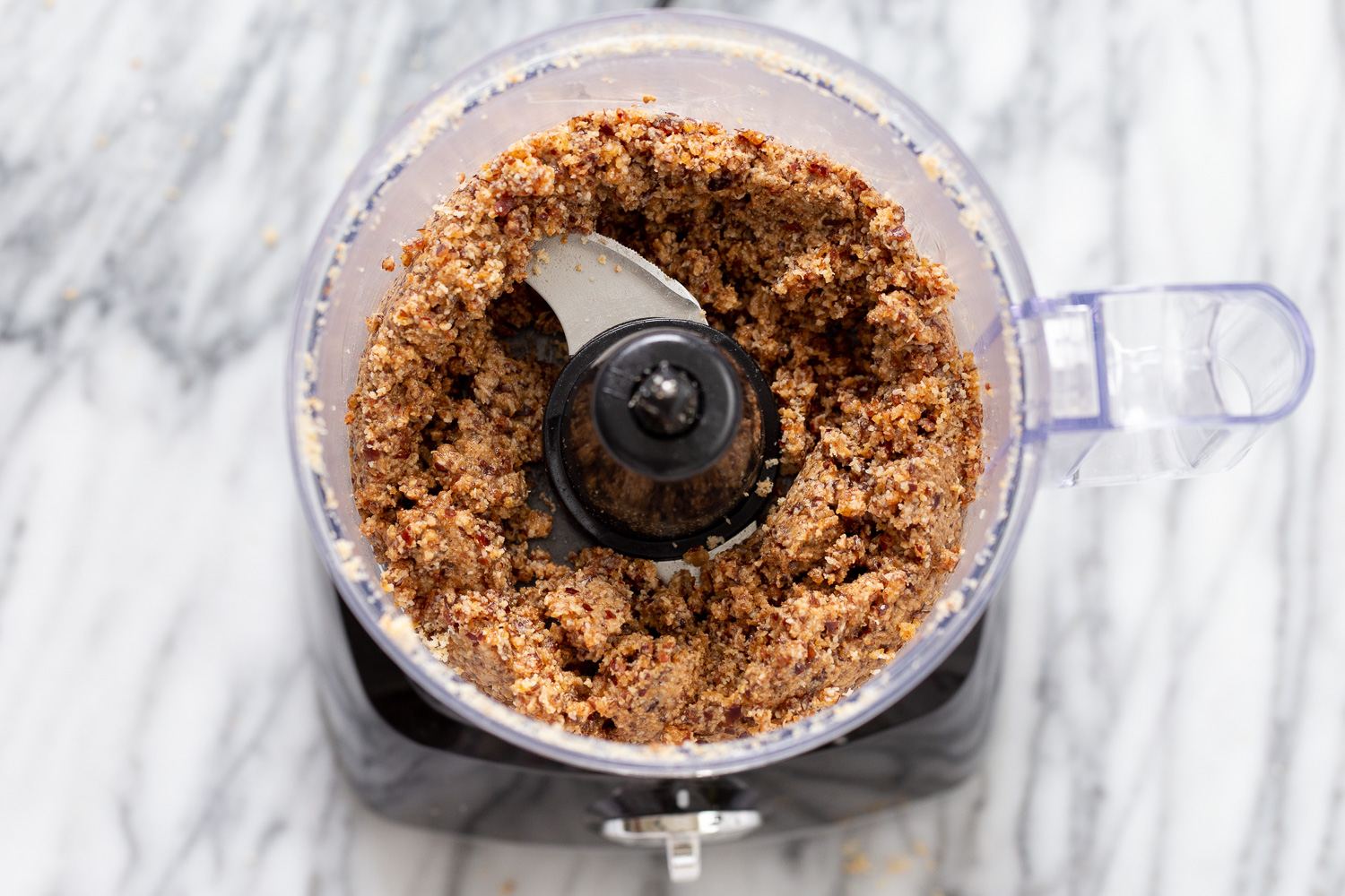 coconut balls coconut dates and almond butter being blended in a food processor to make vegan energy balls