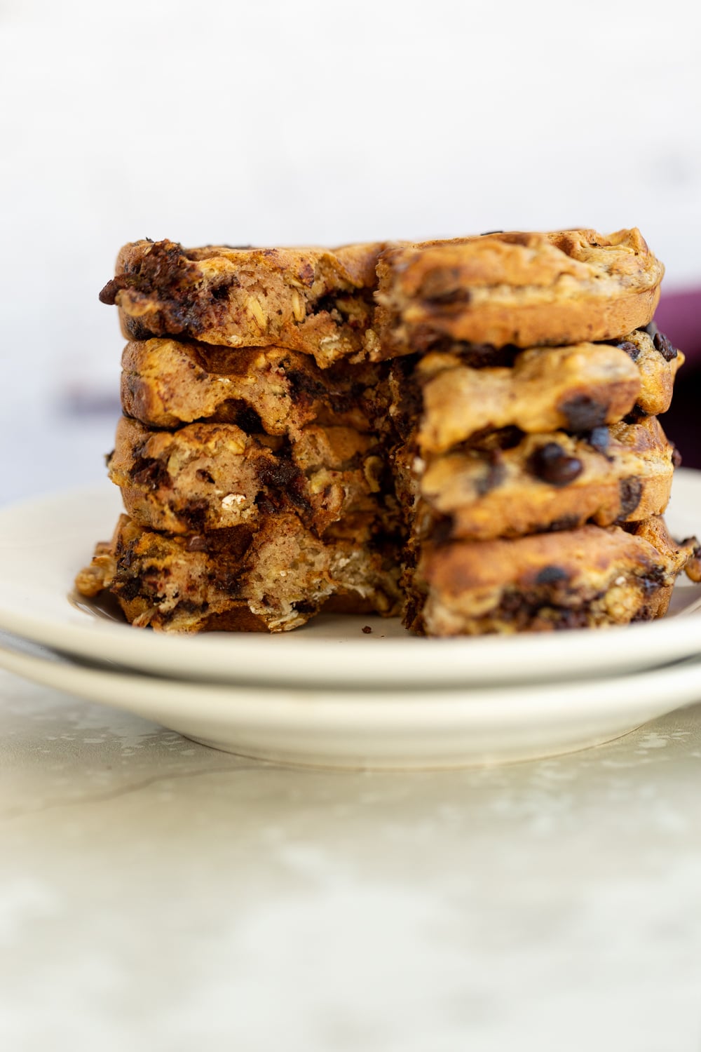 chocolate chip waffles side view of a stack of crispy vegan oatmeal chocolate chip waffles on a white plate