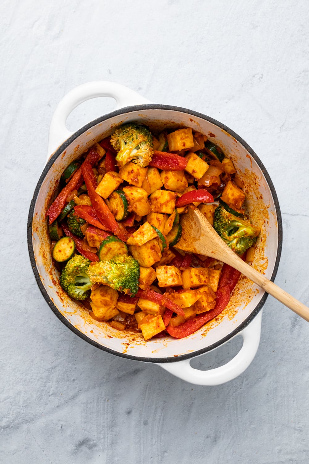 vegetables and potatoes being sauteed with Thai red curry paste to make vegan curry
