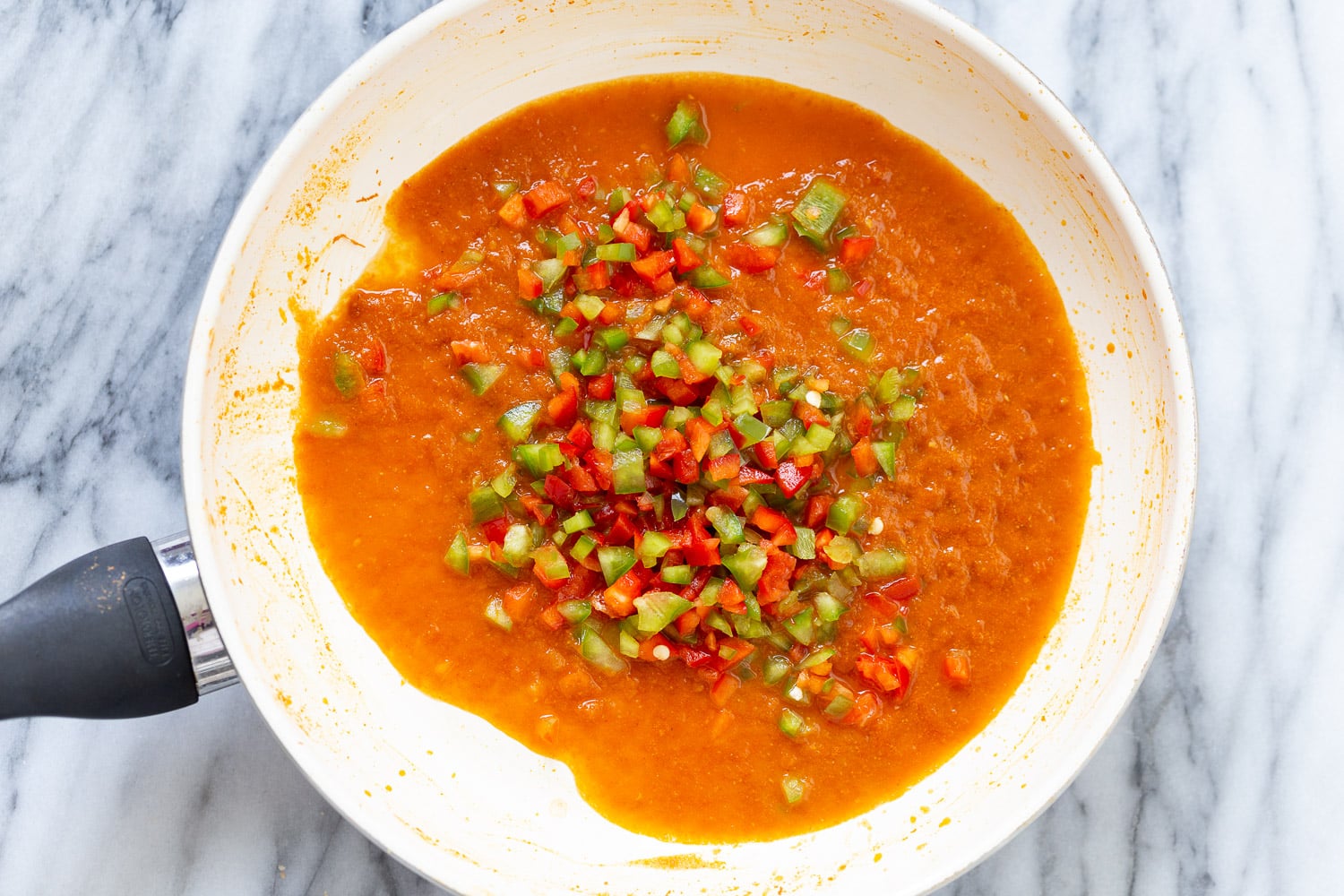 Spanish Cauliflower Rice overhead shot of a saucepan with tomato sauce and diced bell pepper for making Spanish cauliflower rice