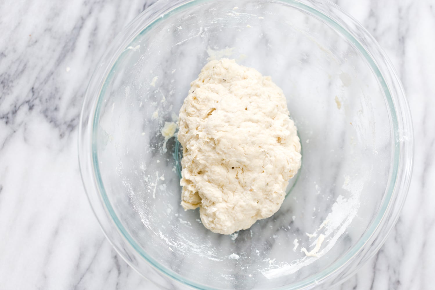 overhead shot of a glass bowl with vegan pizza dough